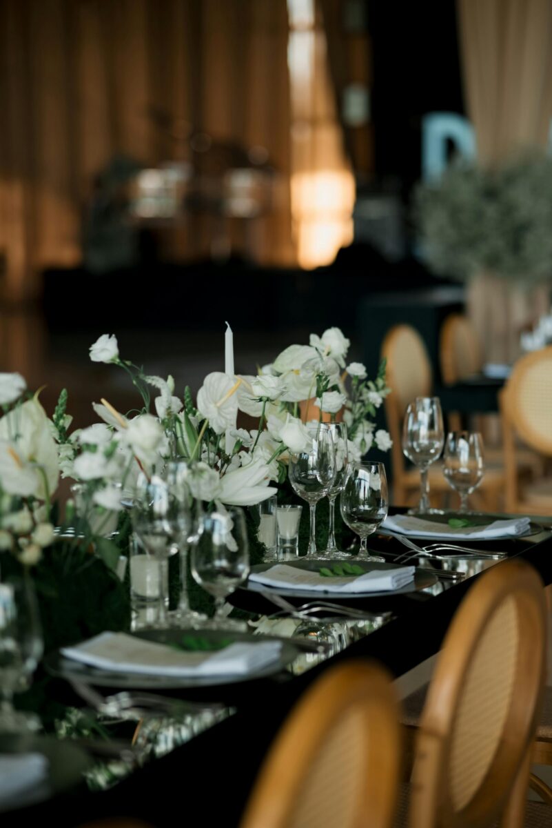 Home Elegant reception table with floral centerpiece and glassware, perfect for weddings.